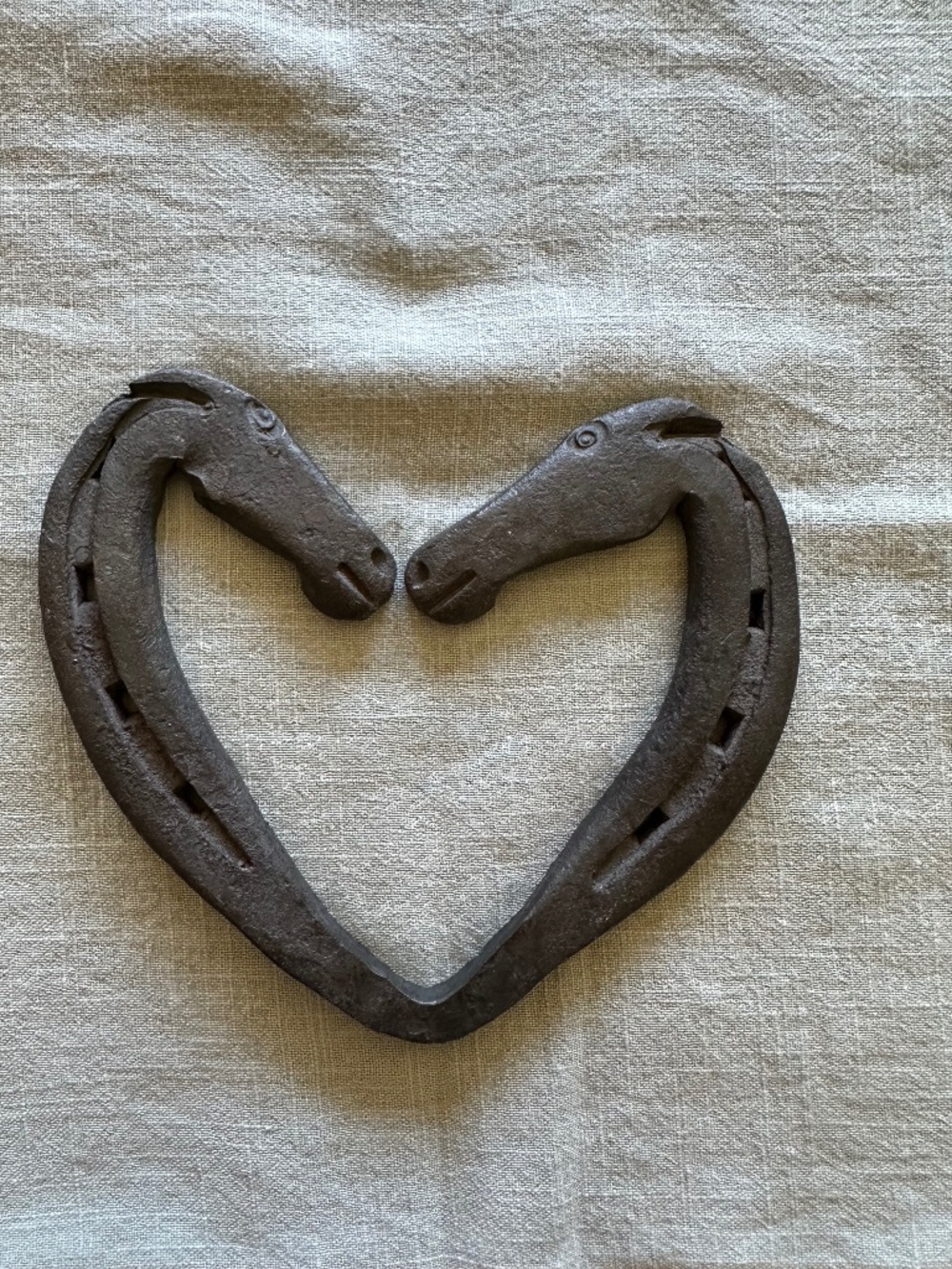 Hand-forged iron heart, two horse heads